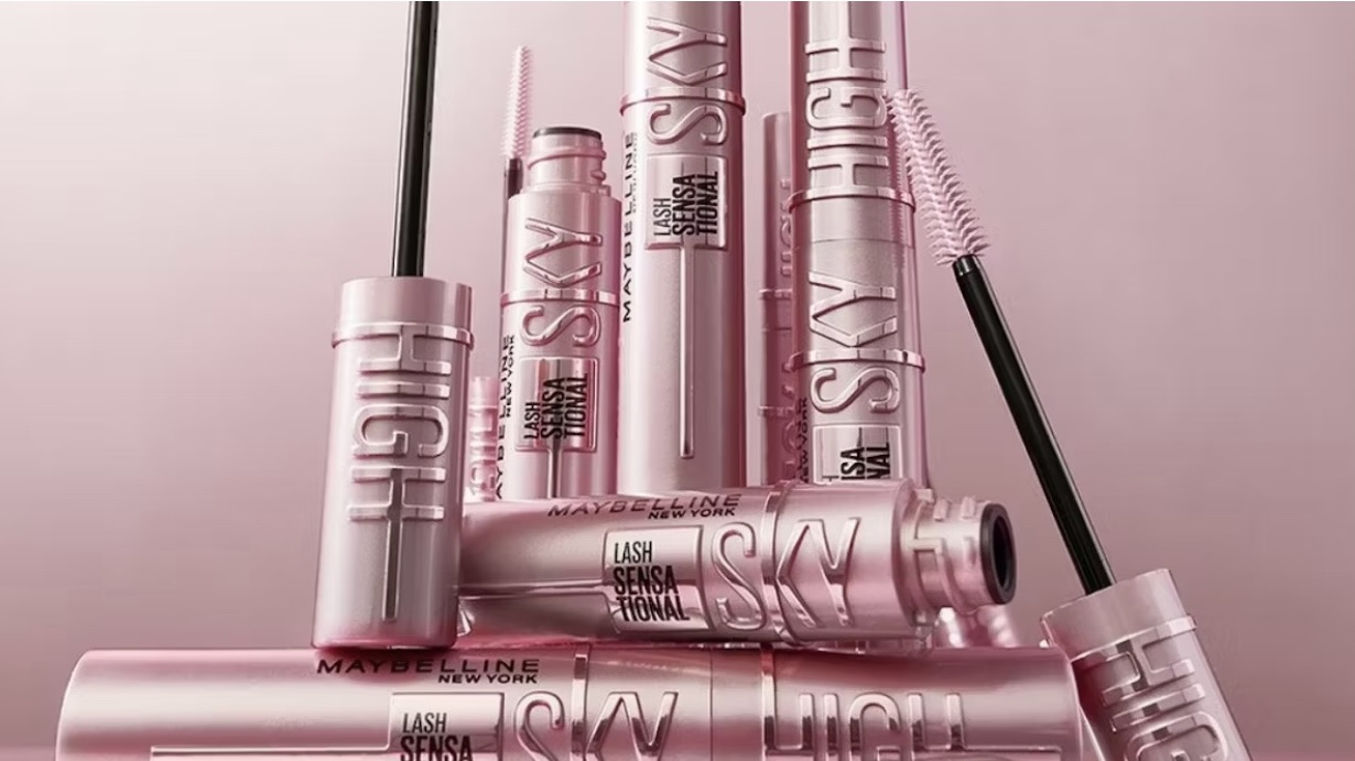 Maybelline Sky High Mascara tubes arranged in a stylized pink product display, highlighting the viral Lash Sensational formula